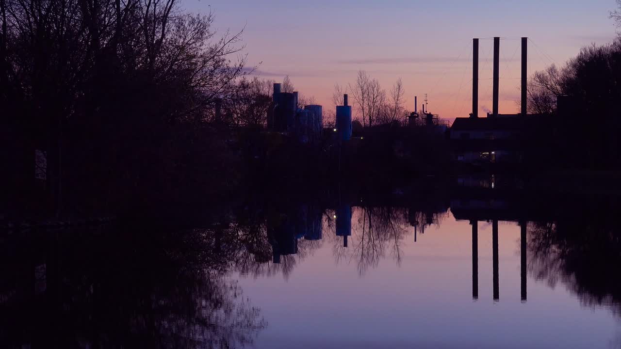 una hermosa puesta de sol sobre un lago con las chimeneas de fondo de la industria