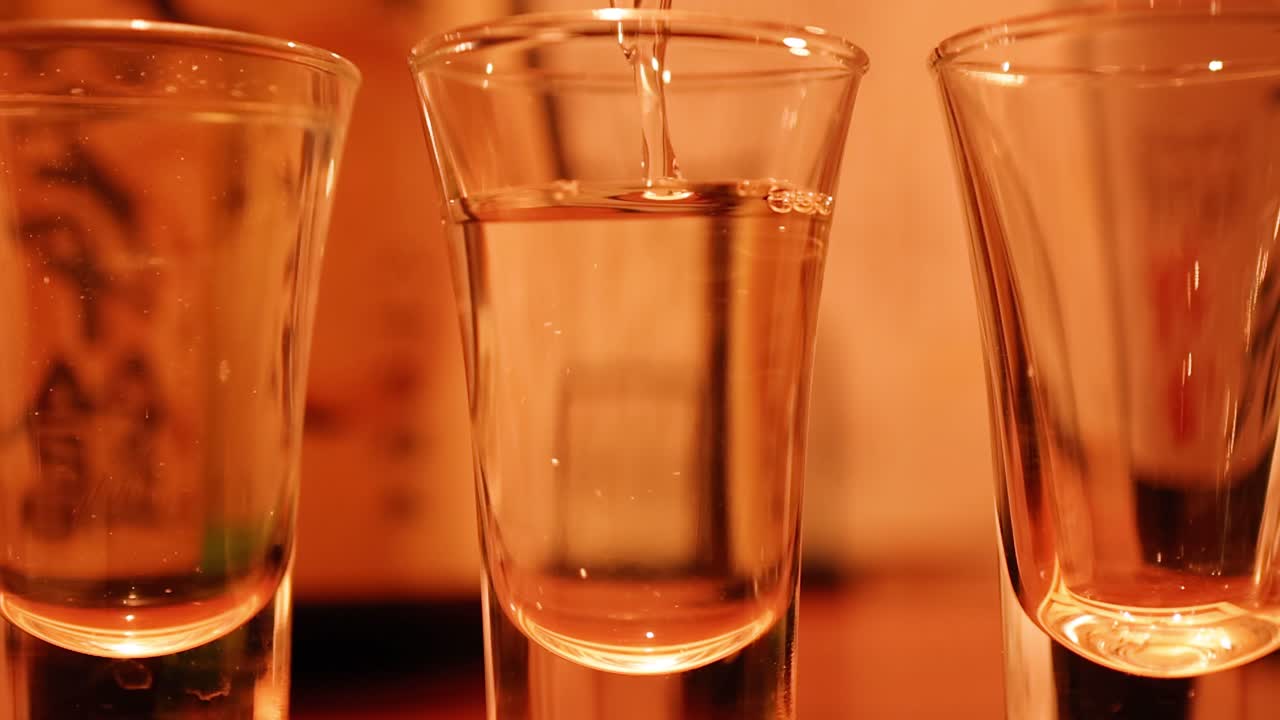 Il vino di riso trasparente si versa in un bicchiere sotto una calda illuminazione ambientale in un bar di Tokyo.