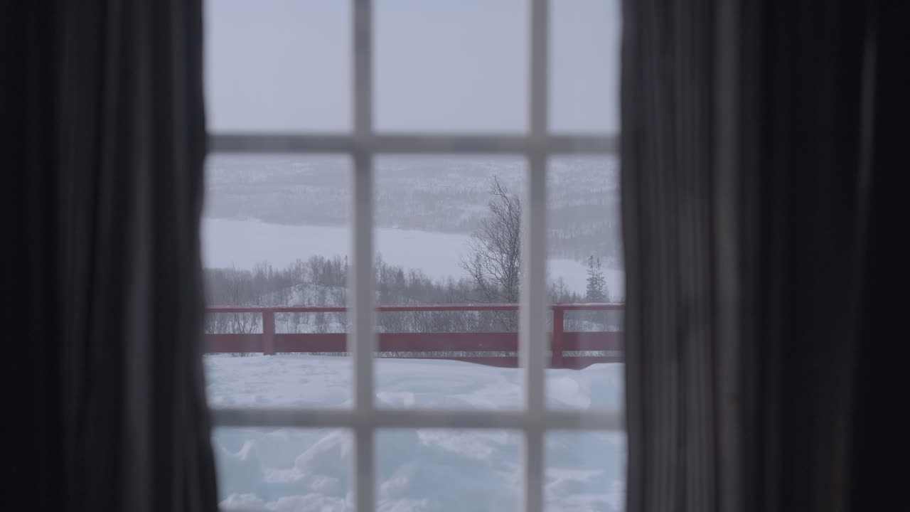 노르웨이의 오두막 창문에서 쾌적한 풍경, 부드럽게 내리는 눈과 눈으로 인 나무들 사이에 자리잡은 매력적인 은 오두막과 함께 평온한 겨울 숲의 장면을 포착합니다.
