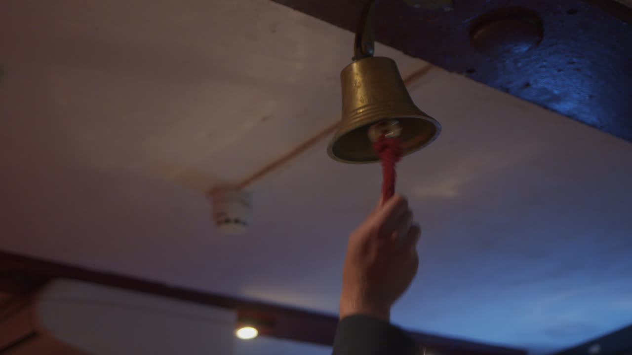 A man ringing a bell above a bar
