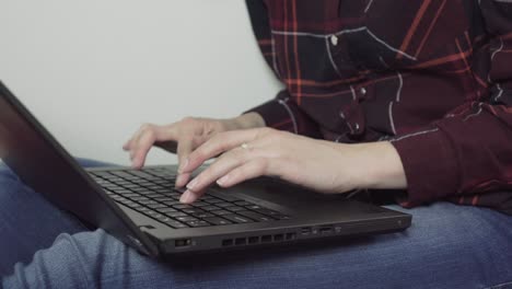 female has laptop on her legs writing to her friends, closeup