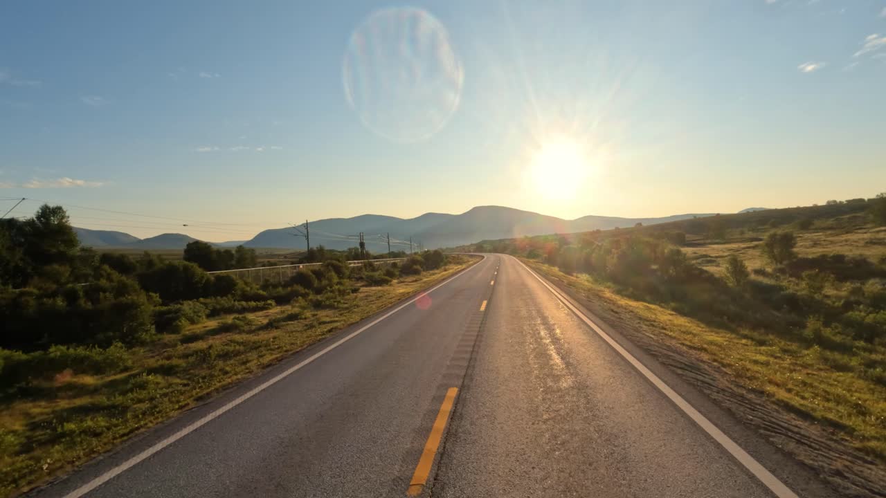 conduciendo un coche en una carretera de noruega al amanecer.