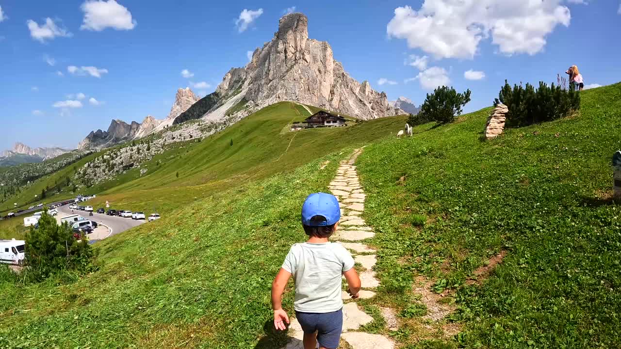 Dziecko biegnące ścieżką na przełęczy Giau w Dolomitach, Włochy