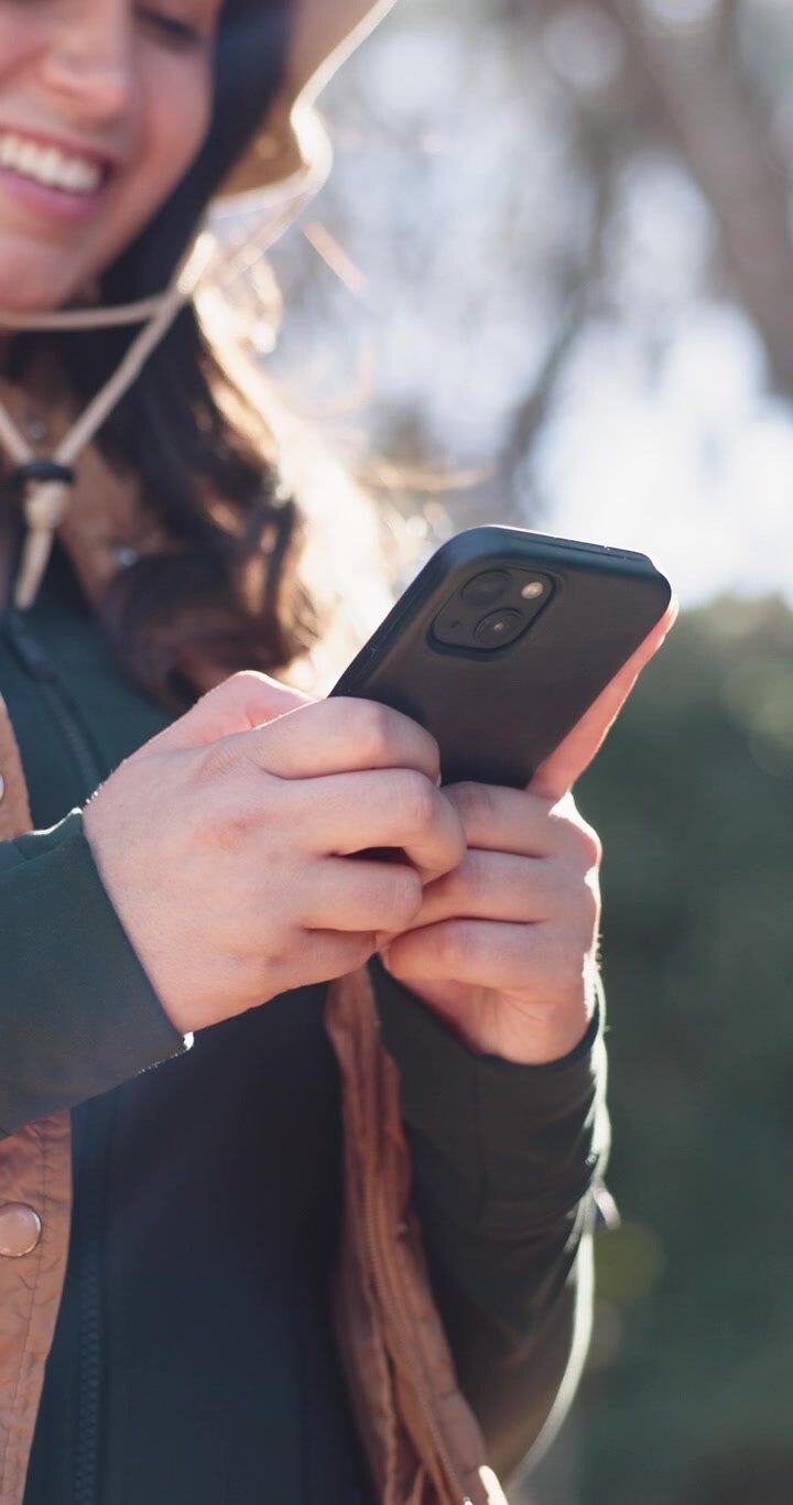Donna sorridente che usa lo smartphone all'aperto nella natura