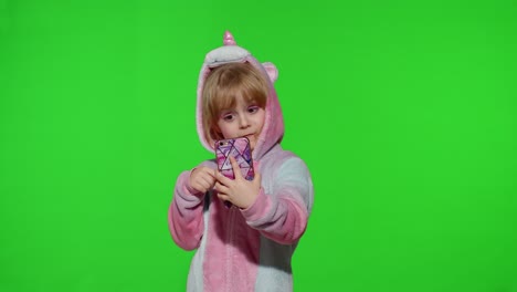 Excited-little-child-girl-in-unicorn-pajamas-using-mobile-cell-phone,-found-out-great-big-win-news