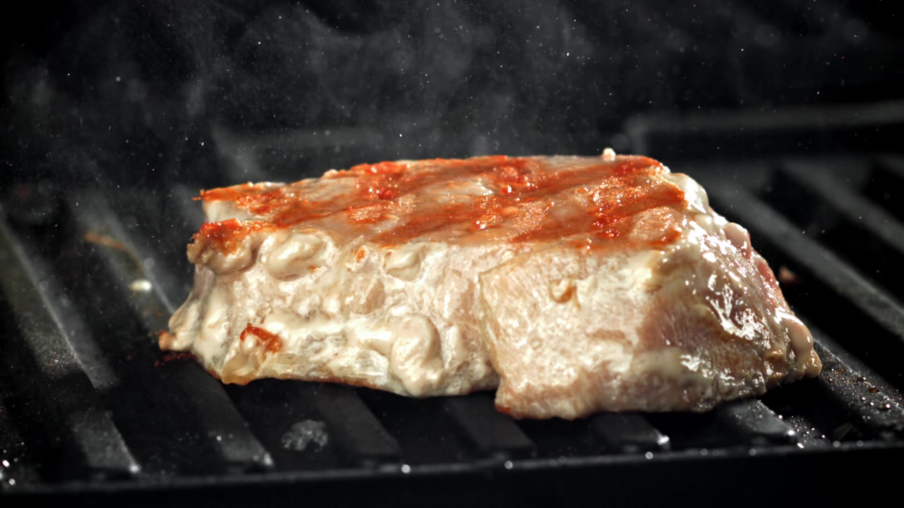 Steak épais grésillant sur un grill chaud