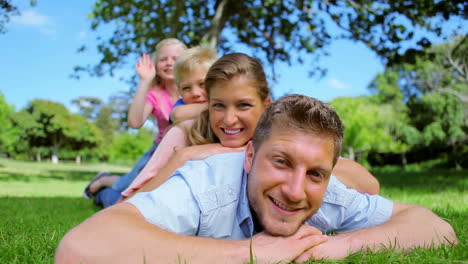 a girl waves her arm as she lies on her family who are laughing while lying on top of each other