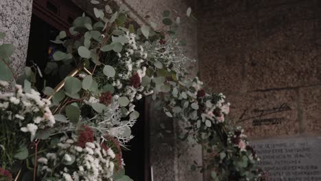 wedding arch of eucalyptus leaves and wildflowers decorates stone wall with natural style