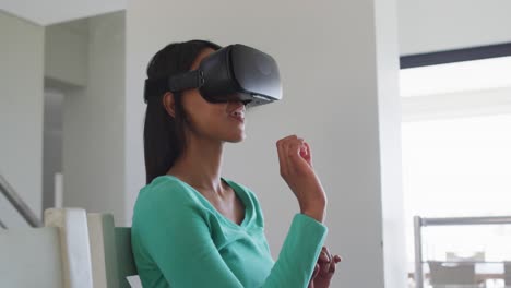 mujer afroamericana usando auriculares vr mientras trabaja desde casa