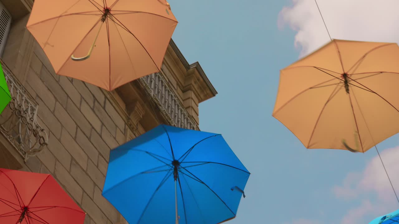 Brightly Coloured Floating Umbrellas In Clear Sky. Low Angle Shot