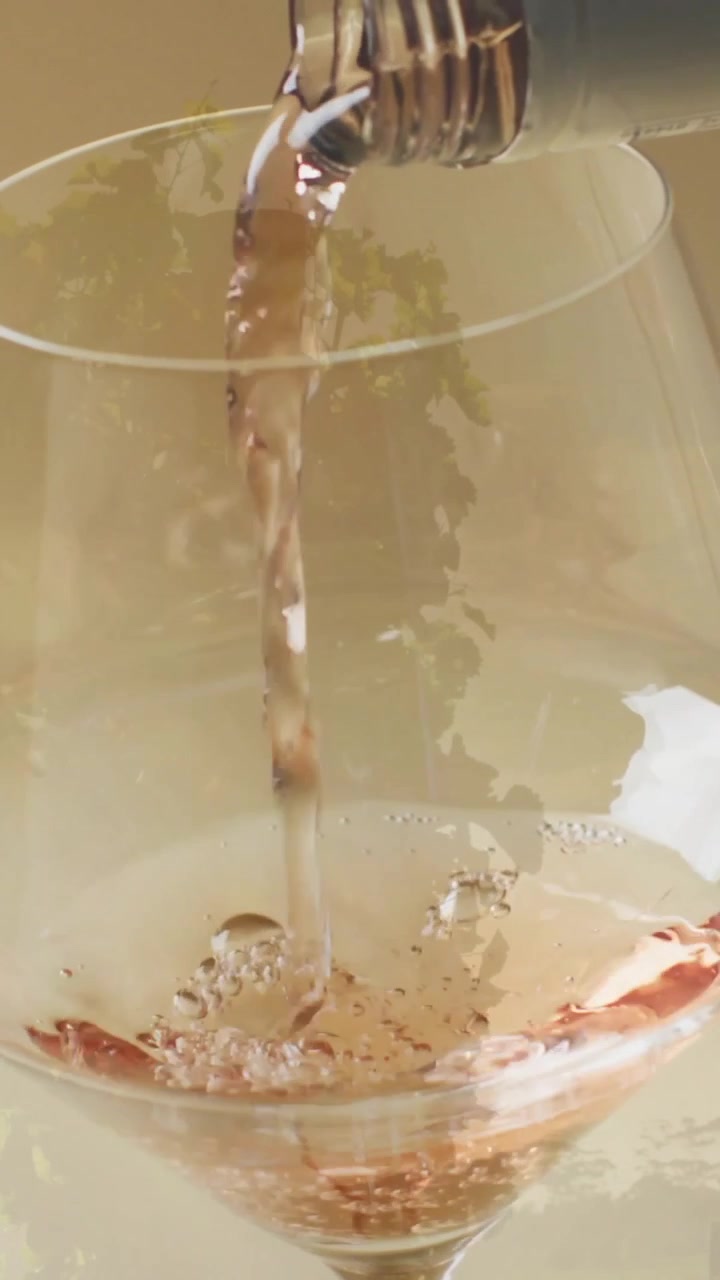 Composizione di vino bianco versato in un bicchiere su sfondo di vigneto