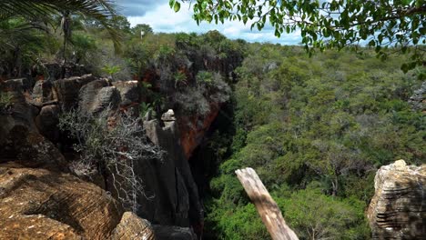 tiro inclinado hacia abajo mirando hacia un agujero en el suelo creado a partir de la cueva lapa doce con una jungla dentro y coloridos acantilados en el parque nacional chapada diamantina en bahia, noreste de brasil