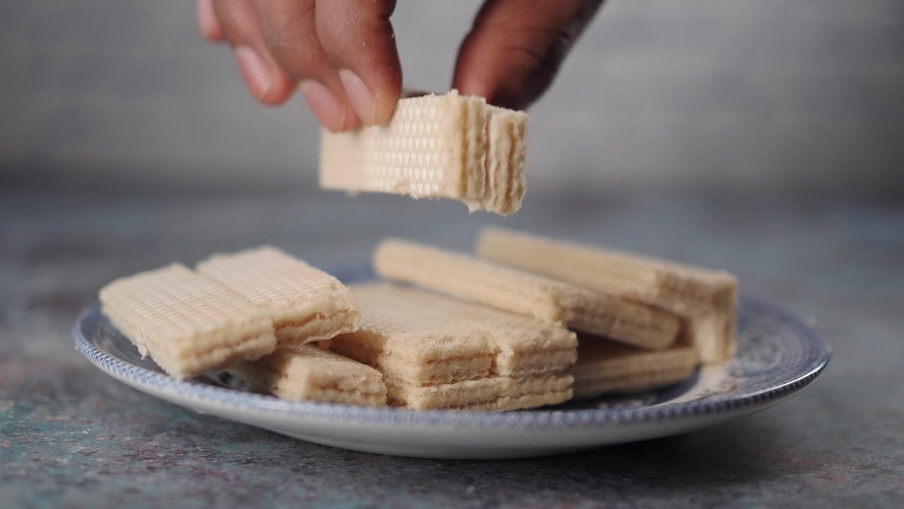 Mano che prende un wafer da un piatto di biscotti