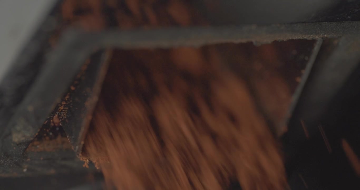 Closeup, macro, super slow motion shot of coffee grounds coming out of a grinder shoot at high speed and stopping abruptly