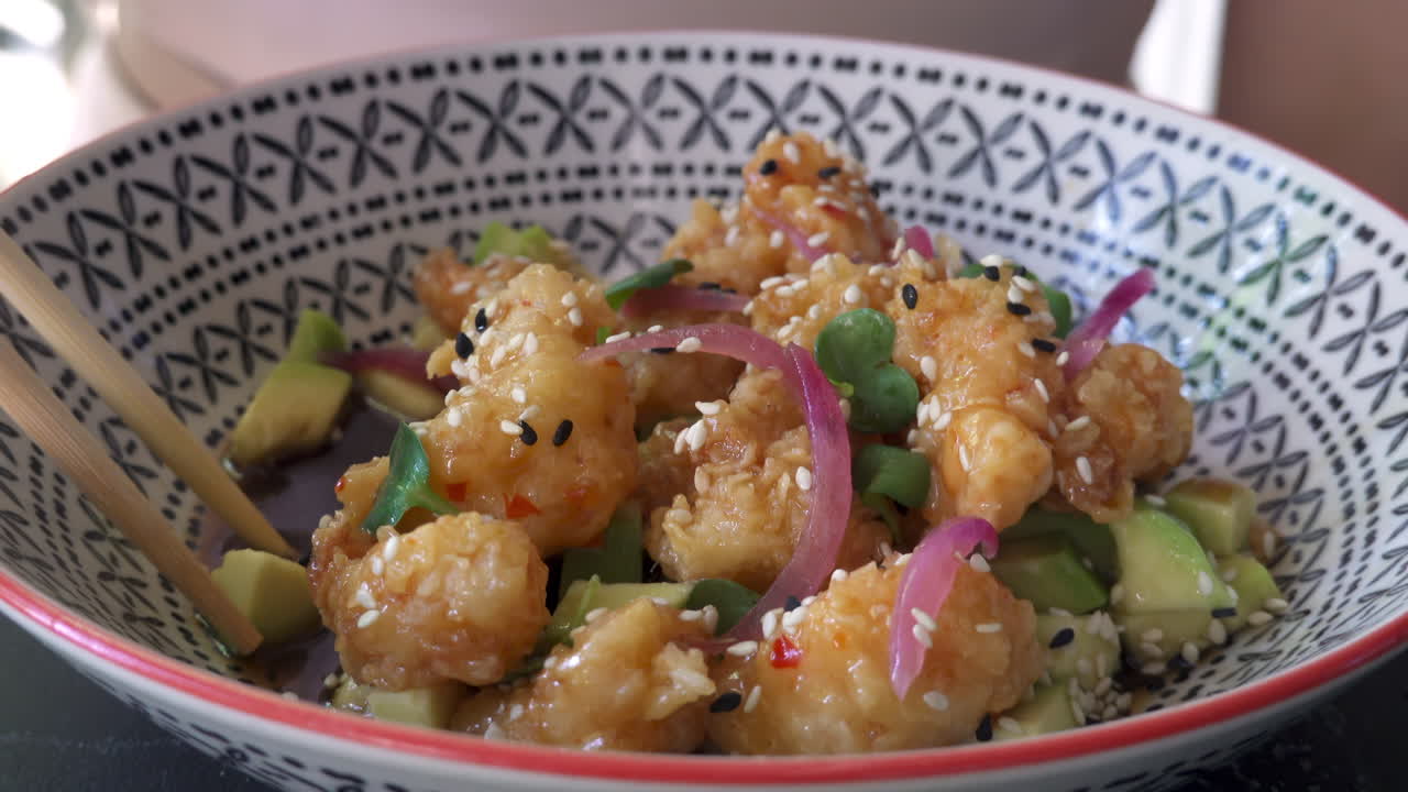 Woman eating prawn popcorn with avocado with chopsticks