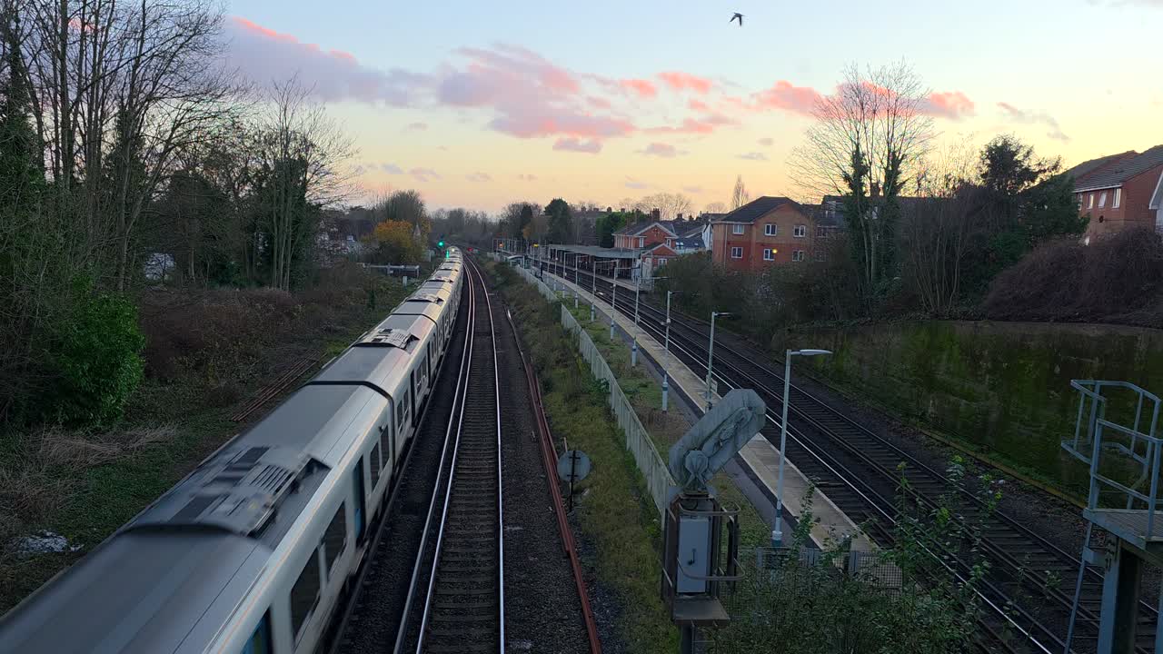 Pendler-tog kører gennem Earlswood station under en farverig aftenhimmel