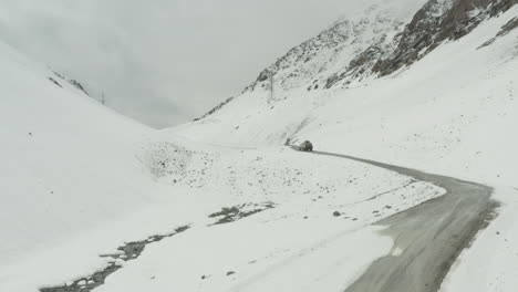 snowy mountain road in kyrgyzstan with a vehicle driving through the snow