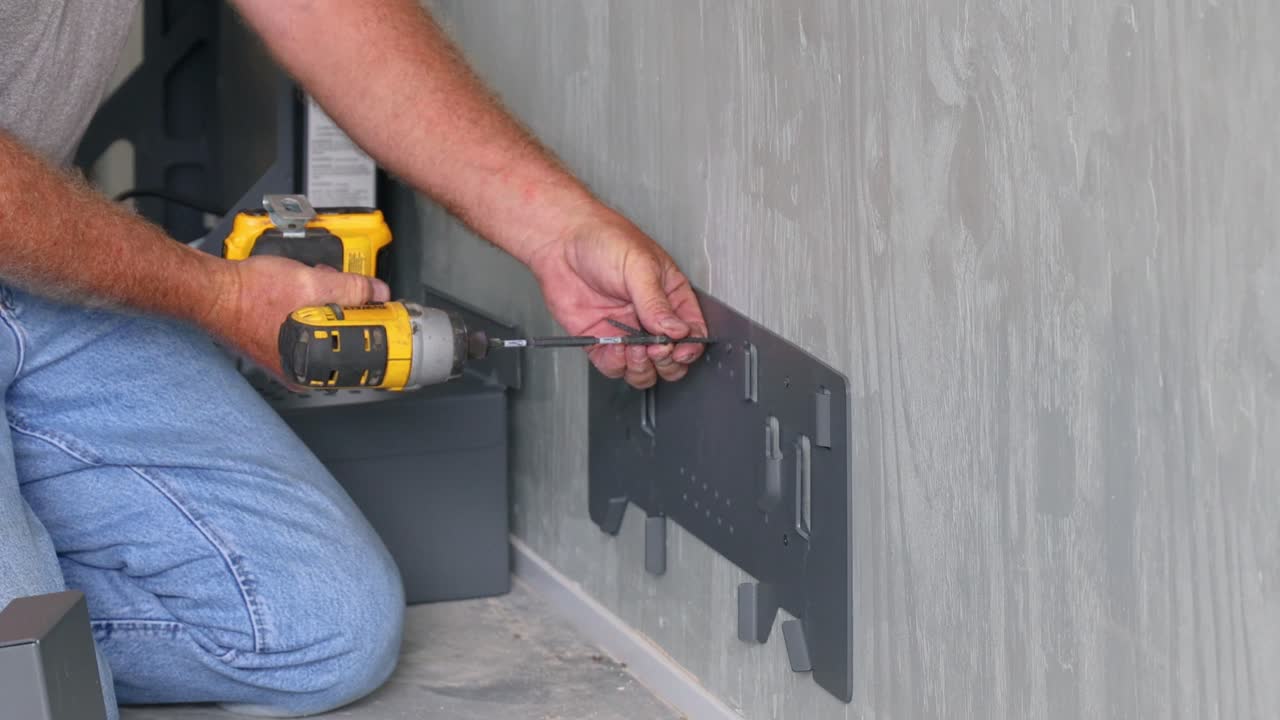 Technician using a drill to install the hanging bracket for the battery box supports
