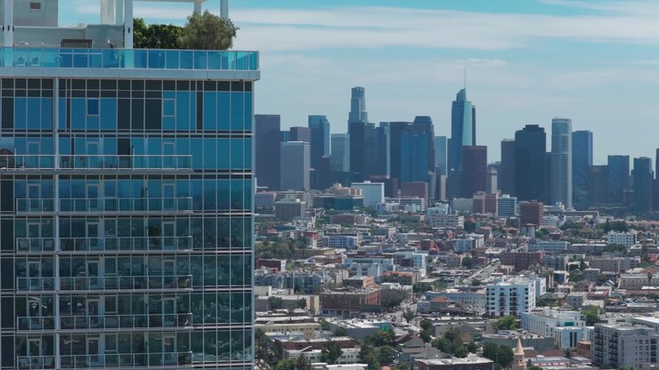 Plano de telefoto revelando o centro de Los Angeles atrás de um arranha-céu de vidro no sul da Califórnia. 4K