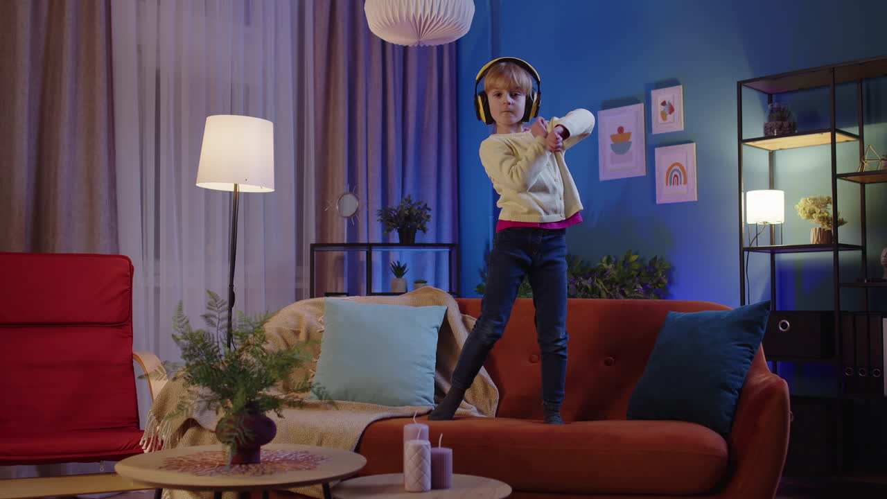 niña feliz niño con auriculares bailando moviéndose al ritmo mientras escucha música en casa sola