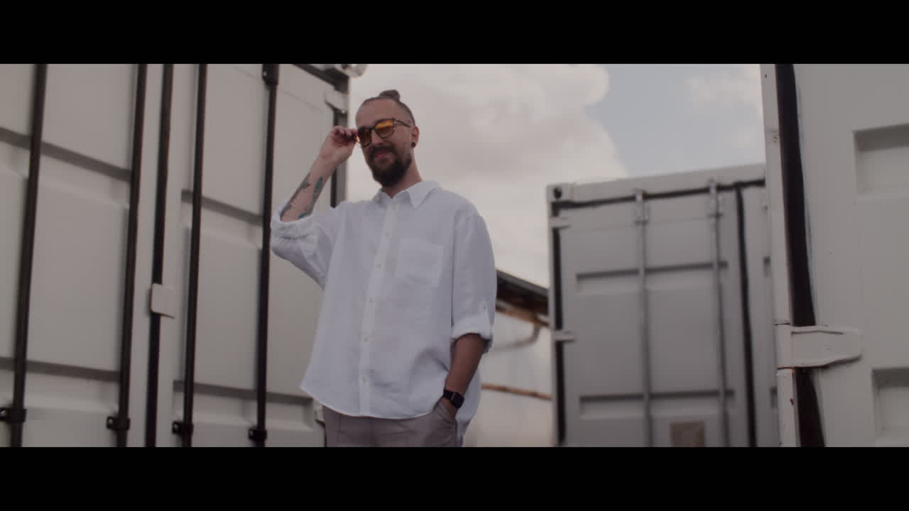 Man in White Shirt and Sunglasses near Shipping Containers