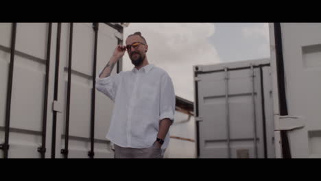 man in white shirt and sunglasses near shipping containers