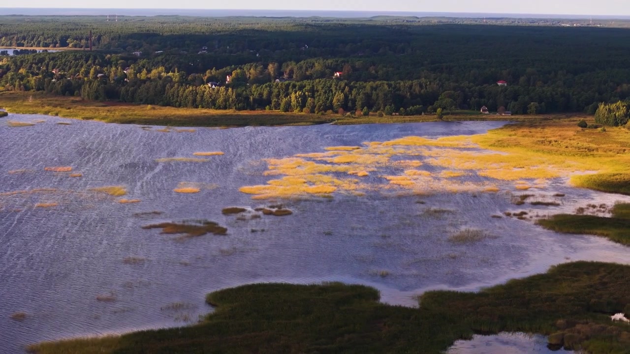 Vista aerea del lago ghiacciato Ķīšezers nel paesaggio rurale lettone, zona boscosa, orizzonte al tramonto