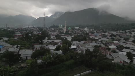 Low-rooftop-aerial-flies-toward-Islam-mosque-in-cloudy-Sembalun-Lombok
