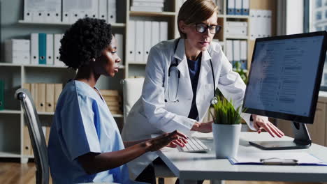 two healthcare professionals collaborating on a computer in a medical office