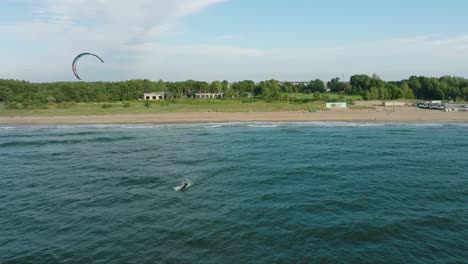 establishing aerial view of a group of people engaged in kitesurfing, sunny summer day, high waves, extreme sport, baltic sea karosta beach , wide drone shot moving backward