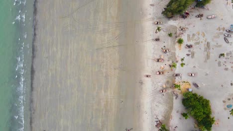 low tide waves roll into beach with tiny wooden boats