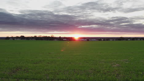 a drone shot over a grassy field at sunset