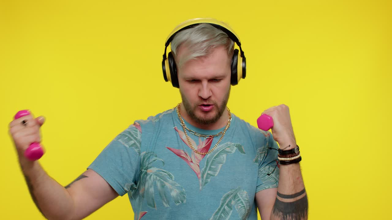 спортивный турист взрослый мужчина слушает музыку через наушники, занимается спортом, поднимает гантели