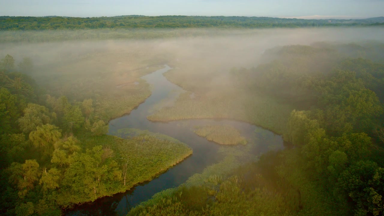 At dawn, a drone captures aerial footage of the mist-covered Huron River near Milford, Michigan.