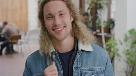 portrait of attractive young man student laughing happy looking at camera enjoying independent lifestyle in urban outdoors busy campus background