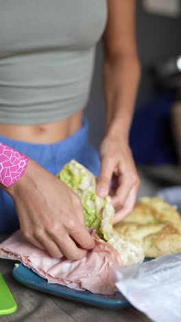 una mujer haciendo un sándwich de jamón.