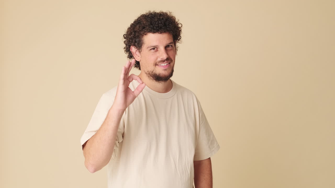 Smiling Man with Curly Hair Makes Okay Gesture