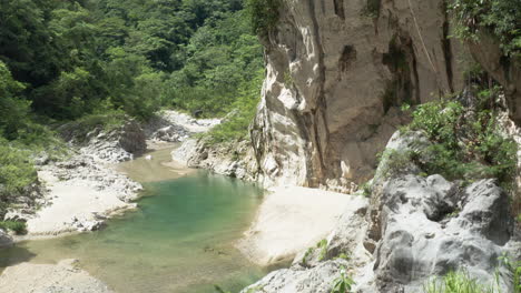 drone ascending through rock formation reveal tranquil nizao river in dominican republic