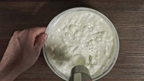 add ingredients to a glass bowl. male hands making dessert. delicious soft sour cream cheese sweet cream. kneading the ingredients. fresh natural homemade yogurt. stuffing for eclairs. curd dessert.