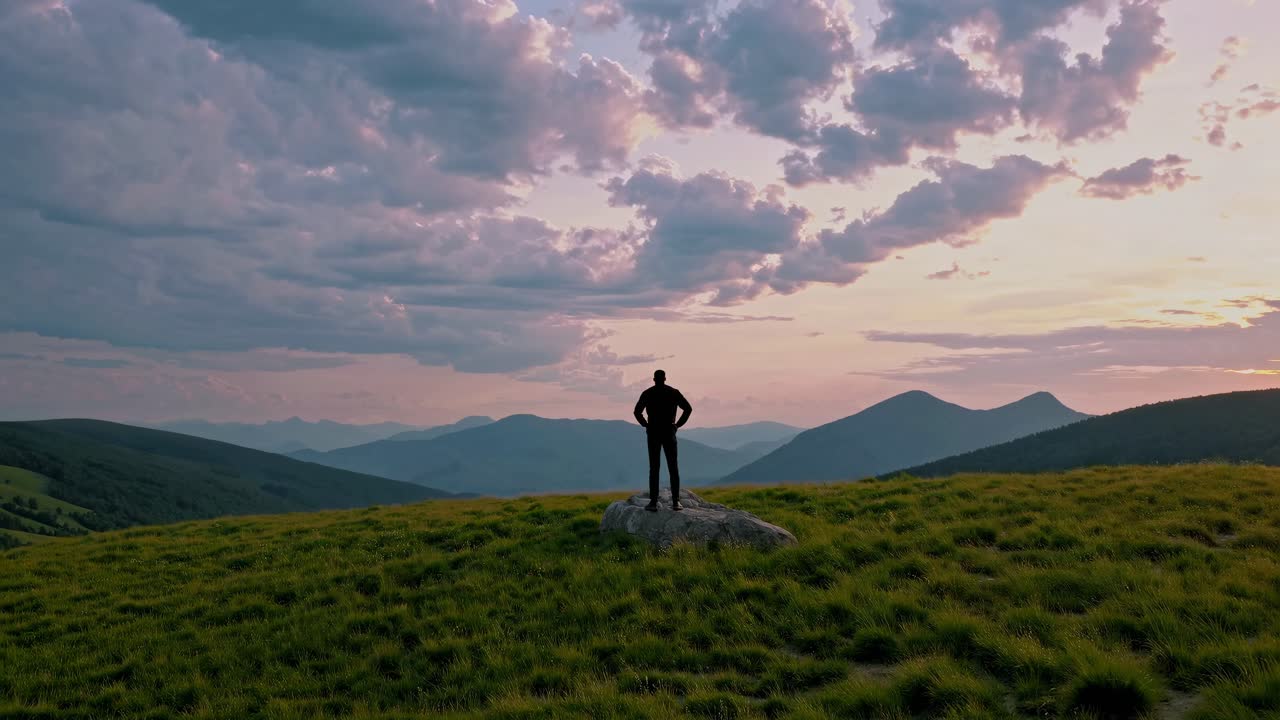 Man Standing on a Mountaintop at Sunset