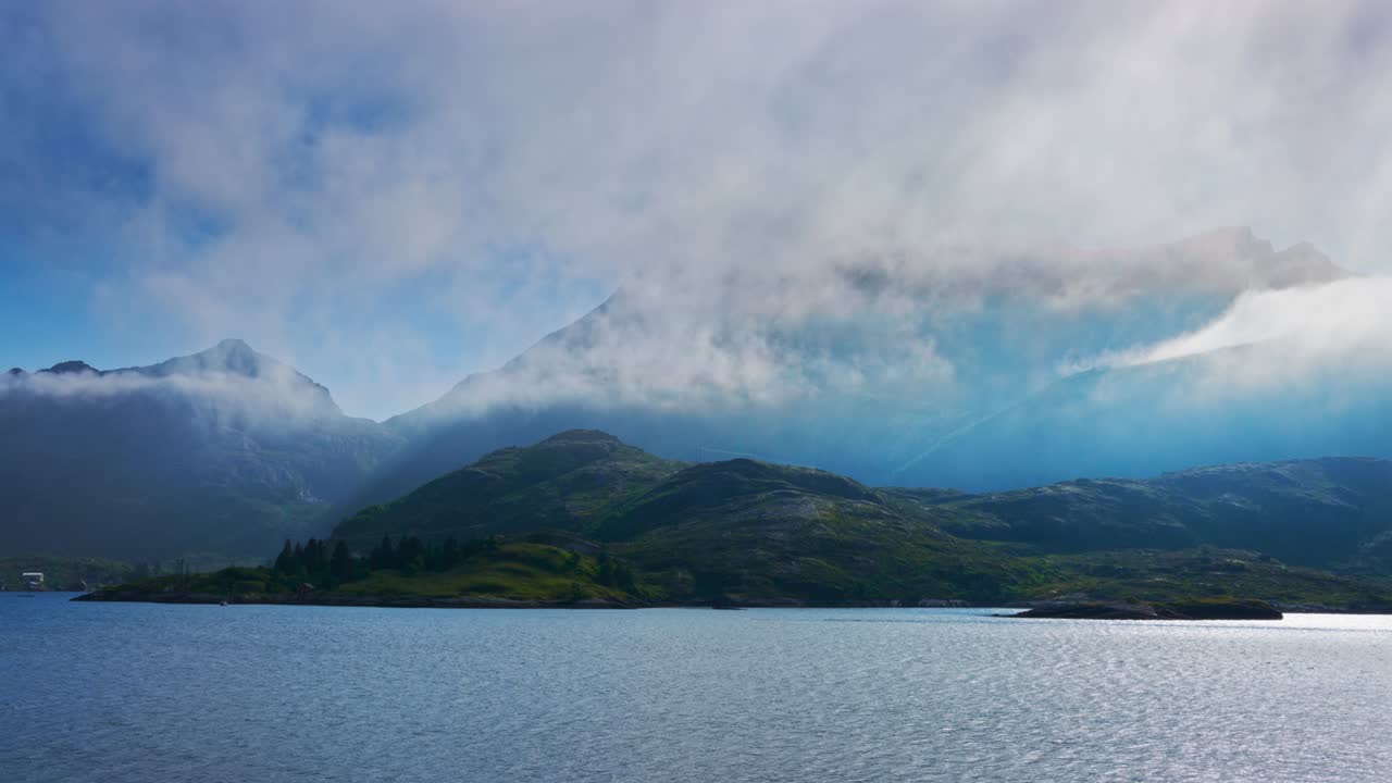 Norwegian Fjord at Summer Time Lapse. Sun shines through sea fog over lush pristine fjord. Lofoten Islands, Northern Norway