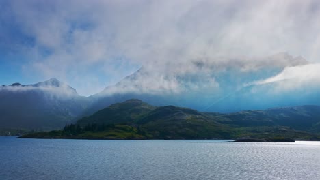 norwegian fjord at summer time lapse. sun shines through sea fog over lush pristine fjord. lofoten islands, northern norway