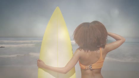 Animation-Einer-Afroamerikanischen-Frau,-Die-Ein-Surfbrett-Am-Sonnigen-Strand-über-Lichtern-Hält