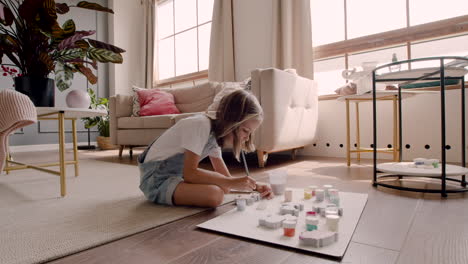 blonde girl sitting on the floor and painting animal pieces in living room 2