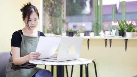 the restaurant manager is surfing the web and communicating. sitting in a coffee cafe, looking over documents.