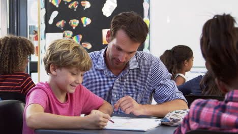 teacher and young schoolboy looking at notebook in class