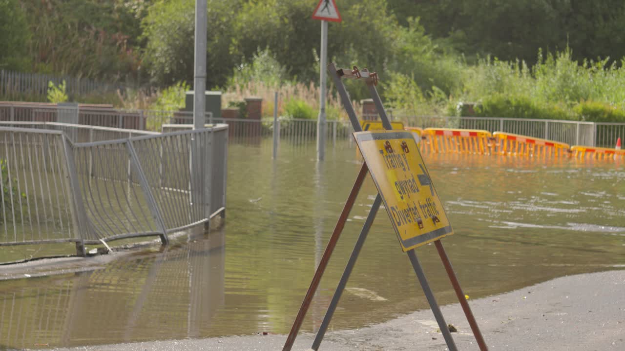 Flooded Road with Bent Metal Pavement Fence with Submerged Hi-Vis Temporary Barrier After Extreme Weather Flash Flood