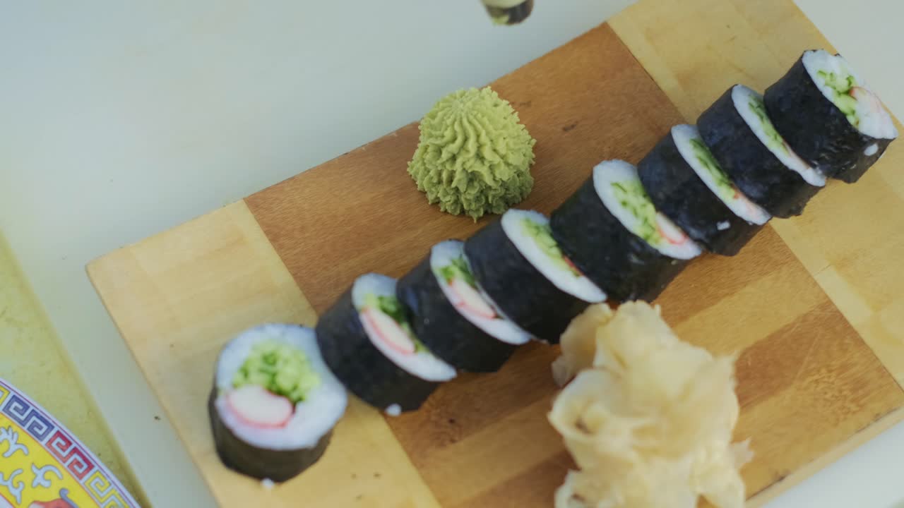 cierre para manos de chef en guantes de cocina exprimiendo salsa de wasabi verde en un plato para rollos preparados