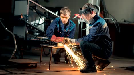 workers wearing mask cuts metal with hand disc grinder abrasive saw