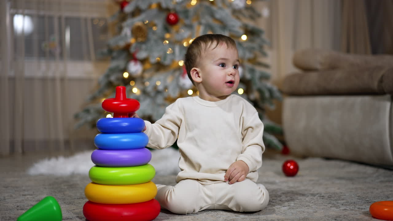 Toddler Playing with Stacking Rings by Christmas Tree
